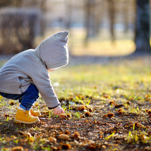 Toddler boy walking outdoors at the warm spring day, focus on child hand